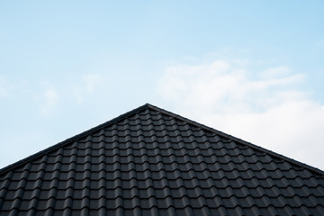 Wall Mural - Black metal tile roof. Roof metal sheets. Modern types of roofing materials. Roof of the house, metal roof tile against the blue sky. Building.