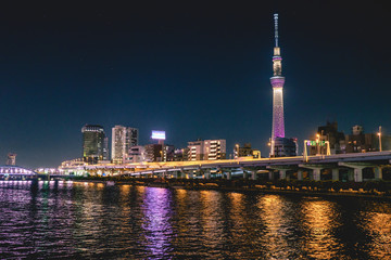 Tokyo cityscape by night, with Sumida river with reflections in front and Tokyo Skytree tower with lights in background