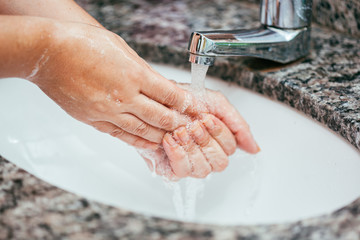  Woman washing her hands with soap and water at the bathroom sink. Coronavirus and Covid-19 prevention