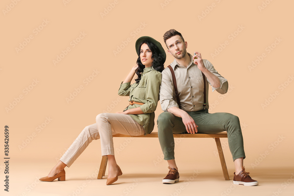 Stylish young couple with perfume on color background