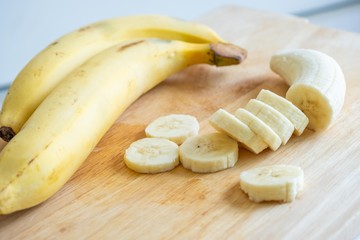 Slices or chopped yellow banana on cutting board.