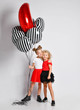 Two nice smiling kids girls in skirts and t-shirts with big air balloons stand together hugging  