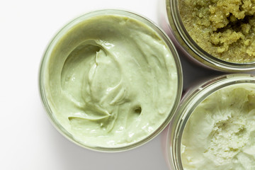 A natural ingredients green body mousse in a jar on white background. Skin care, spa and clean cosmetic concept. Health and beauty. Homemade mask or cream with matcha and kale. Top view. Close-up