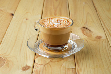 Cappuccino in transparent glass cup on wooden table