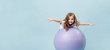 Curly-haired funny girl plays on a gymnastic ball