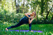 © Smile - Young woman doing yoga exercises in summer city park.