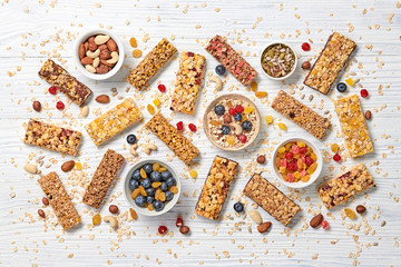 Energy healthy snack. Cereal granola bar with nuts and dry fruit berries. Fitness diet food. Protein muesli bars isolated on white wood. Sport oatmeal bar, top view