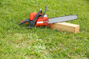 Wall Mural -  orange chainsaw on grass close up with copy space.