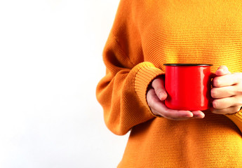 Woman in orange cozy sweater holding red cup of hot drink on white background. Copyspace, close up, mockup