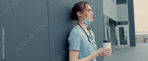 Fotografía Portrait of tired exhausted nurse or doctor having a coffee break outside in the morning