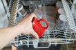 Eine rote Tasse in den Geschirrspüler hineinlegen herausnehmen
