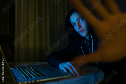 Fotografía Hacker with a laptop hiding his face by hand
