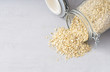Transparent oatmeal jar with oats spread out on grey background. Copy space, close up. 