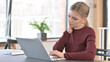 © stockbakers - Young Woman with Neck Pain using Laptop in Office