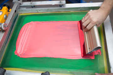 Silk screen printing. Serigraphy. Color paints and fabric. Plastisol paint and squeegee.