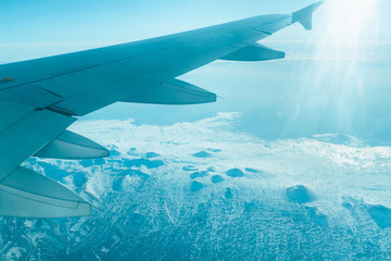 Aircraft wing and ground as seen through window of an aircraft. The view through the porthole, stock photo.