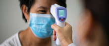 Female Doctor Check Asian Woman Body Temperature Using Infrared Forehead Thermometer (thermometer Gun) For Virus Symptom At Hospital. Corona Virus, Covid-19, Quarantine Or Virus Outbreak Concept