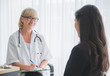 © Nopphon - Senior female doctor meet the patient discussing and making notes about symptom problem. Health care and client service in medicine concept.