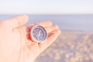 Sticker - Male hand with magnetic compass on sea shore.