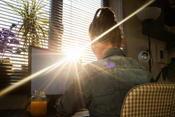 Wall Mural - home office woman working on computer in sunset lights