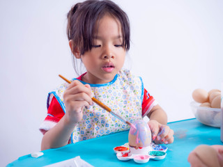 girl coloring easter eggs with colors and brush