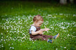 © Elena  - Charming boy among green grass and beautiful daisies on a summer day. A small child has fun in the fresh air. Baby explores the nature of