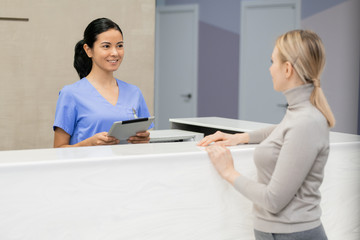 Poster - Pretty young consultant with tablet standing by reception counter