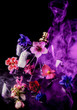 © Антон Фрунзе - A glass perfume bottle shatters and bright spring flowers and clouds of blue and purple vapor burst out of it against a dark background