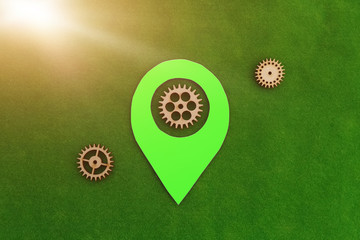 Fototapete - Green geolocation sign, wooden gears on a green background. Location detection mechanism.