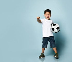 Cute boy playing football, happy child, young male teen goalkeeper enjoying sport game, holding ball, isolated portrait of a preteen smiling and having fun