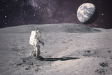 Fototapeta Kosmos - Astronaut on rock surface with space background. Elements of this image furnished by NASA