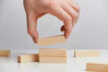 Concept Of Rebuilding A Business After Bankruptcy. Hand Holds Wooden Blocks On A White Background.