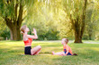 Family summer outdoor sport activity. Young Caucasian mother with child toddler boy doing workout yoga fitness in park. Woman mom doing physical exercises together with a little kid outside.