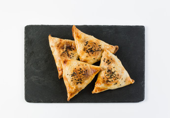 Chicken leek puff pastry samsa on a dark background, top view