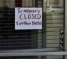 Handwritten Sign Reading Temporary Closed Further Notice On A Glass Door With Security Gate Behind Door, April 4, 2020, In New York.
