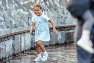 Happy beautiful girl running through the spray of water.