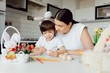 © Serhii - Mother and her son painting colorful easter eggs. Family celebrating Easter. Parent and kid play indoors. Decorated home and spring flowers.