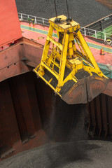 Wall Mural - Loading coal from cargo barges onto a bulk vessel using ship cranes  in offshore coal cargo terminal.
