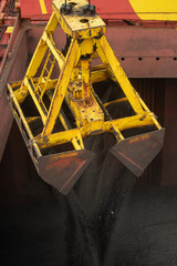 Wall Mural - Loading coal from cargo barges onto a bulk vessel using ship cranes  in offshore coal cargo terminal.
