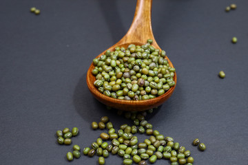 Close up view of mung beans or green beans in a  wooden spoon isolated on dark background.  Food and health concept