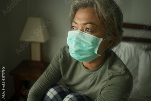 scared and worried middle aged woman 50s with grey hair and protective mask during covid-19 virus crisis home lockdown quarantine thoughtful in fear and stress