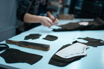 man shaping leather for shoe with knife on factory