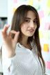 © H_Ko - Cheerful female clerk showing all right symbol with her fingers at office workplace headshot