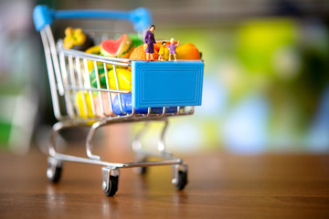 Miniature people of family and shopping cart in supermarket.food and beverage concept