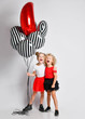 Two happy laughing singing kids girls in skirts and t-shirts with air balloons stand together hugging