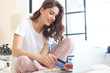 © ty - Happy natural brunette using credit card and laptop in bedroom.