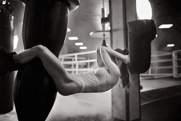 Wall Mural - Woman training abs on punching bag, monochrome.