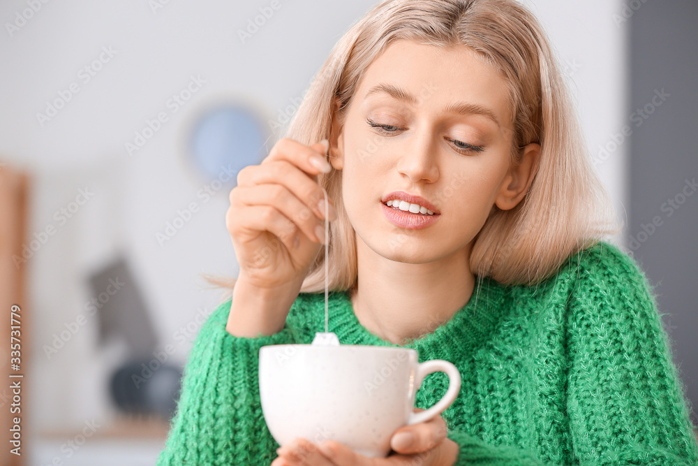 Beautiful young woman drinking tea at home