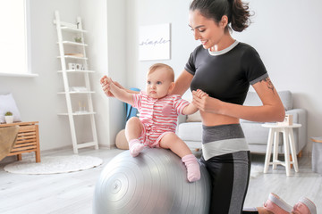 Sticker - Young sporty mother and her baby doing exercises with fitball at home