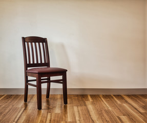 Dark wooden chair on light wood floor in front of white wall